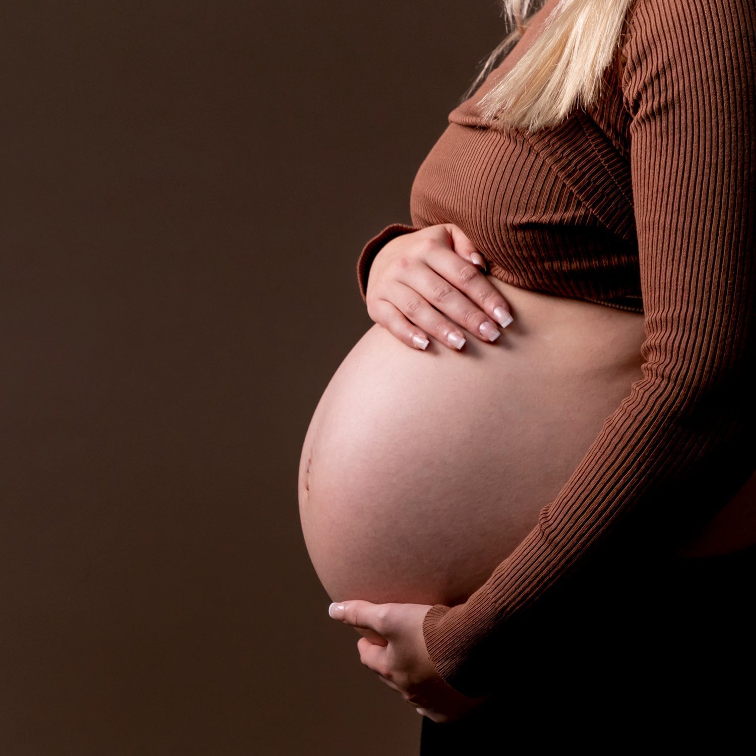  Une femme enceinte montre son ventre nu.