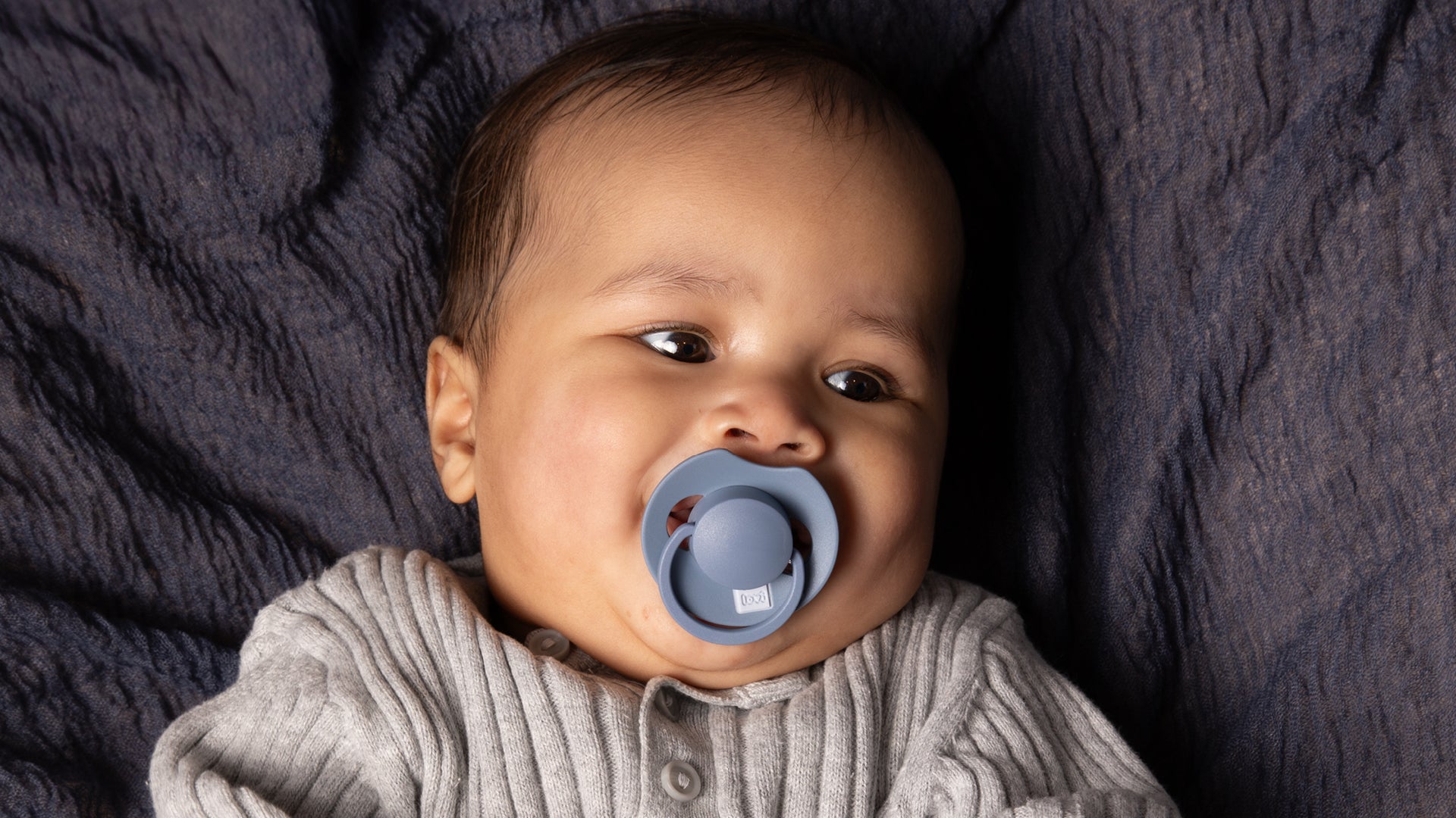 Bébé repose paisiblement avec une tétine Difrax LOVI bleue de la collection Harmony, conçue pour répondre aux besoins délicats de votre petit.