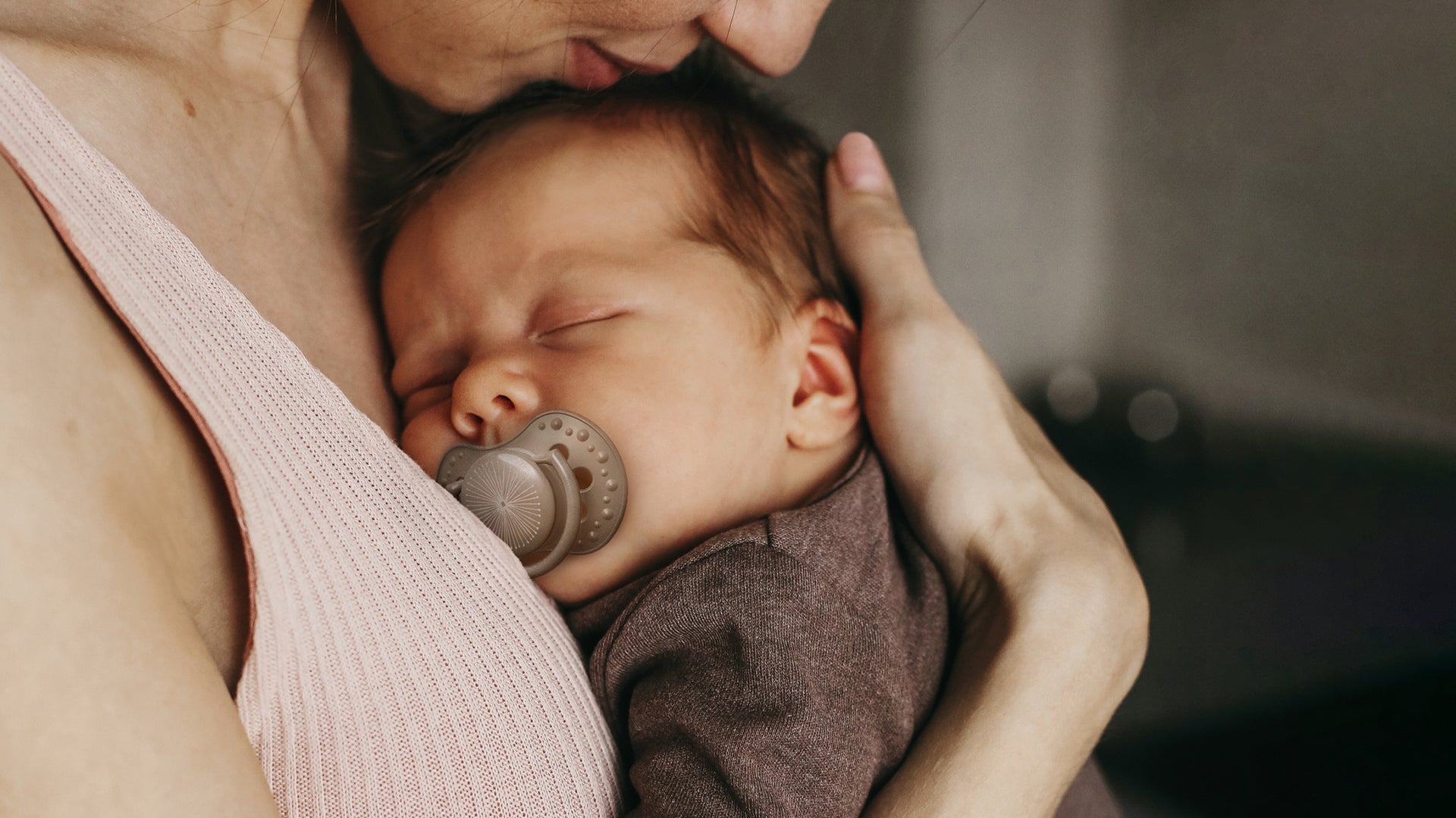 Un nouveau-né est allongé contre la poitrine de sa maman. Le bébé a une sucette Difrax LOVI pour nouveau-né.