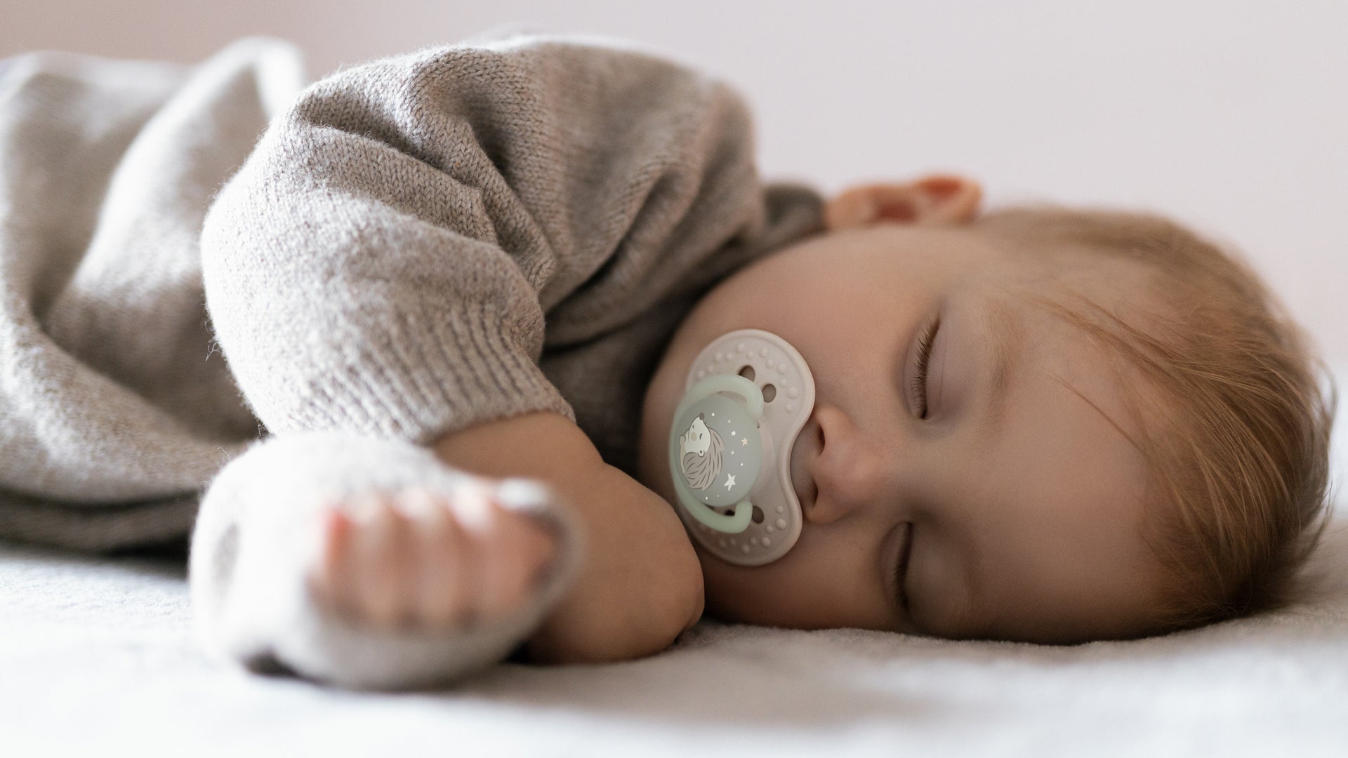 Un tout-petit dort dans son lit avec une sucette Difrax LOVI de la collection Night&Day.