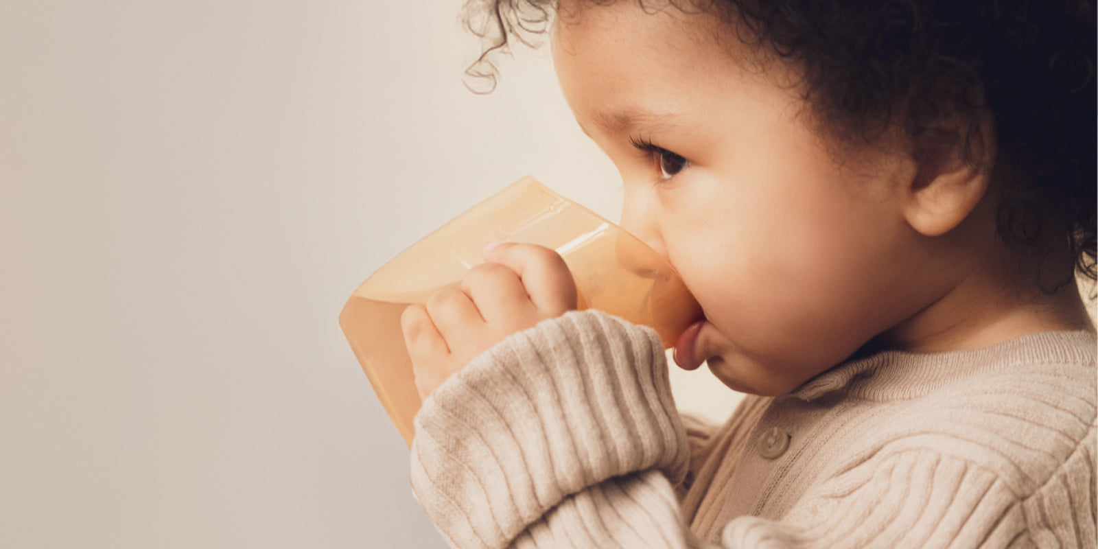 Bébé utilisant un gobelet et un bavoir pendant le repas