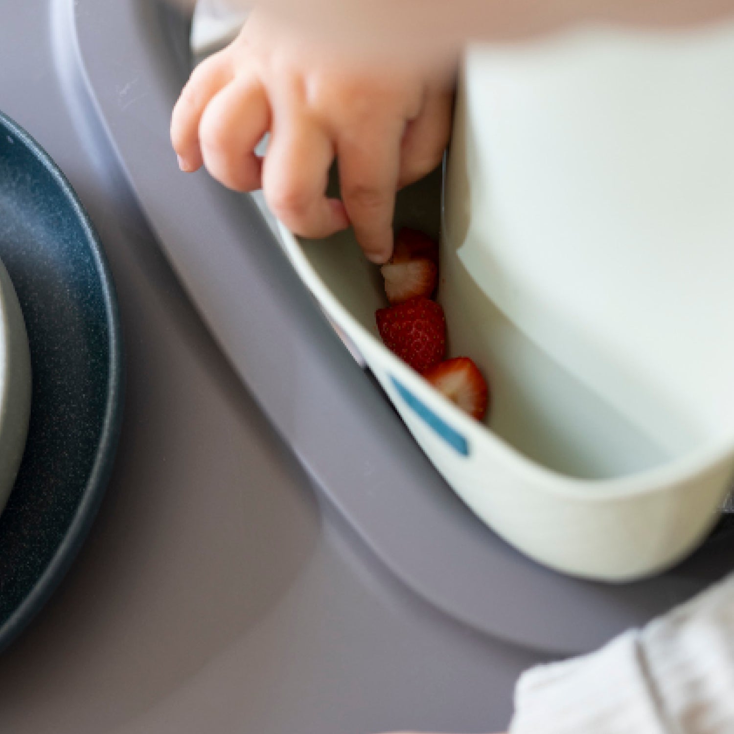Détail du bavoir en silicone pistache montrant sa capacité à attraper les aliments comme les fraises