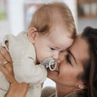 Mère tenant et câlinant son bébé avec la sucette Difrax LOVI Buddy Bear Nouveau-né 0-2 mois en silicone, petit bouclier, anneau phosphorescent
