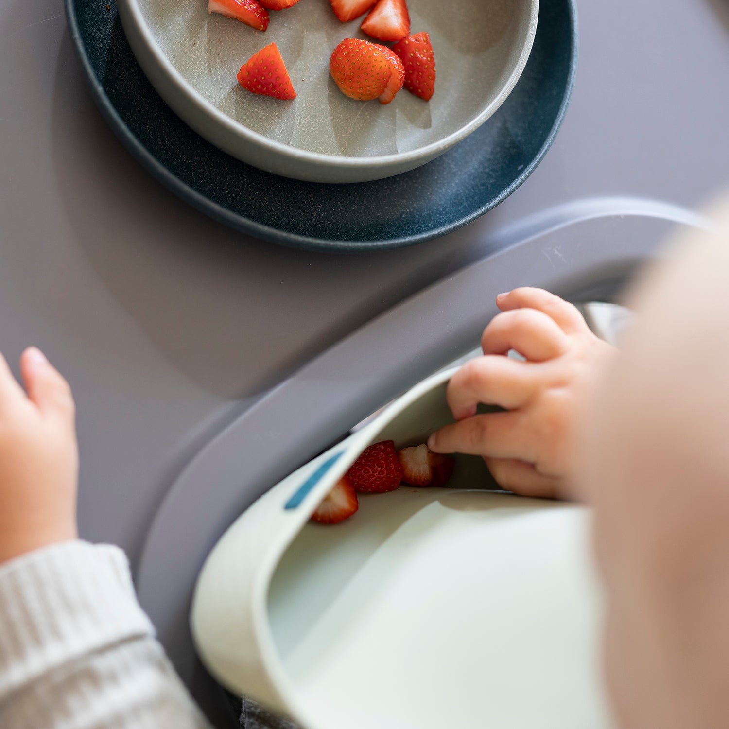 Un enfant en bas âge choisit sa nourriture dans sa plaque en silicone. 