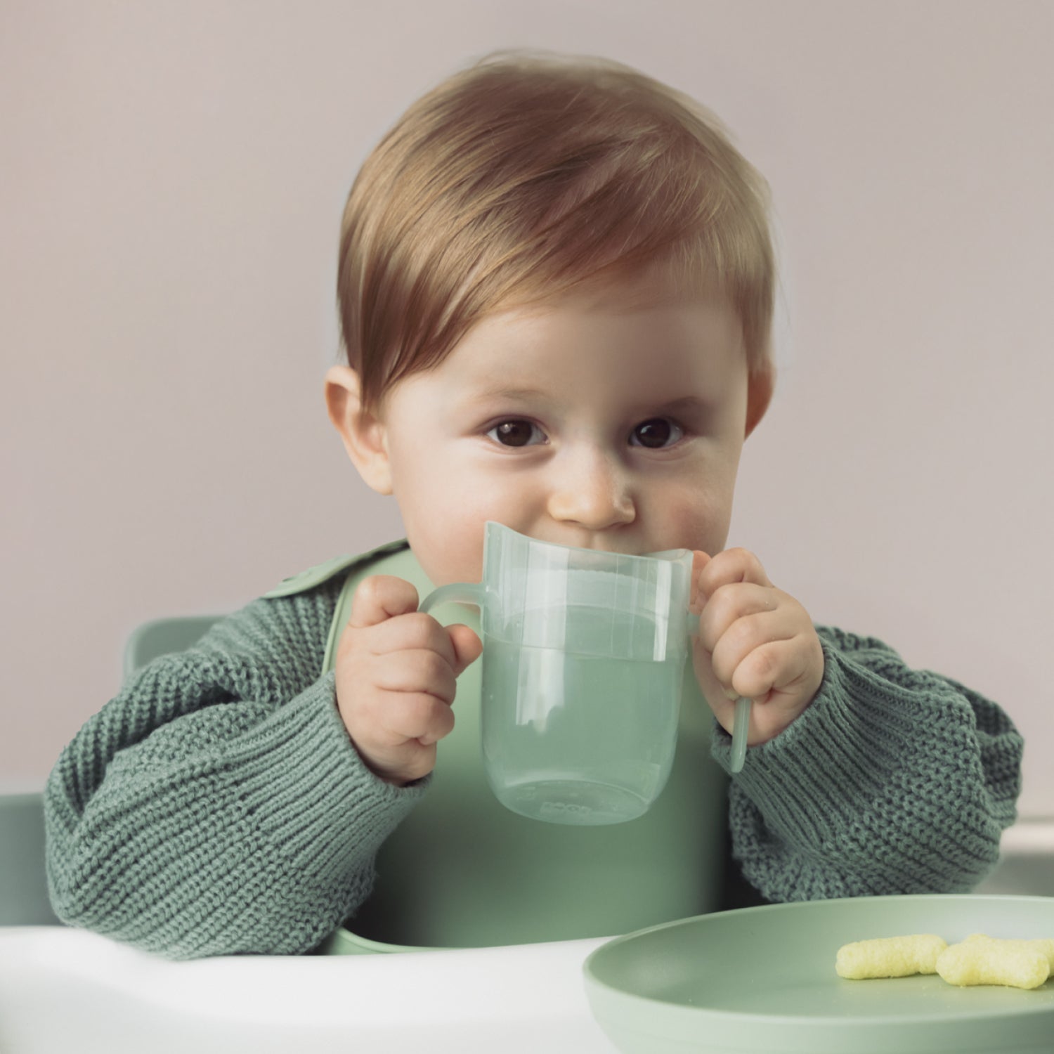 Enfant buvant avec un gobelet vert Genius