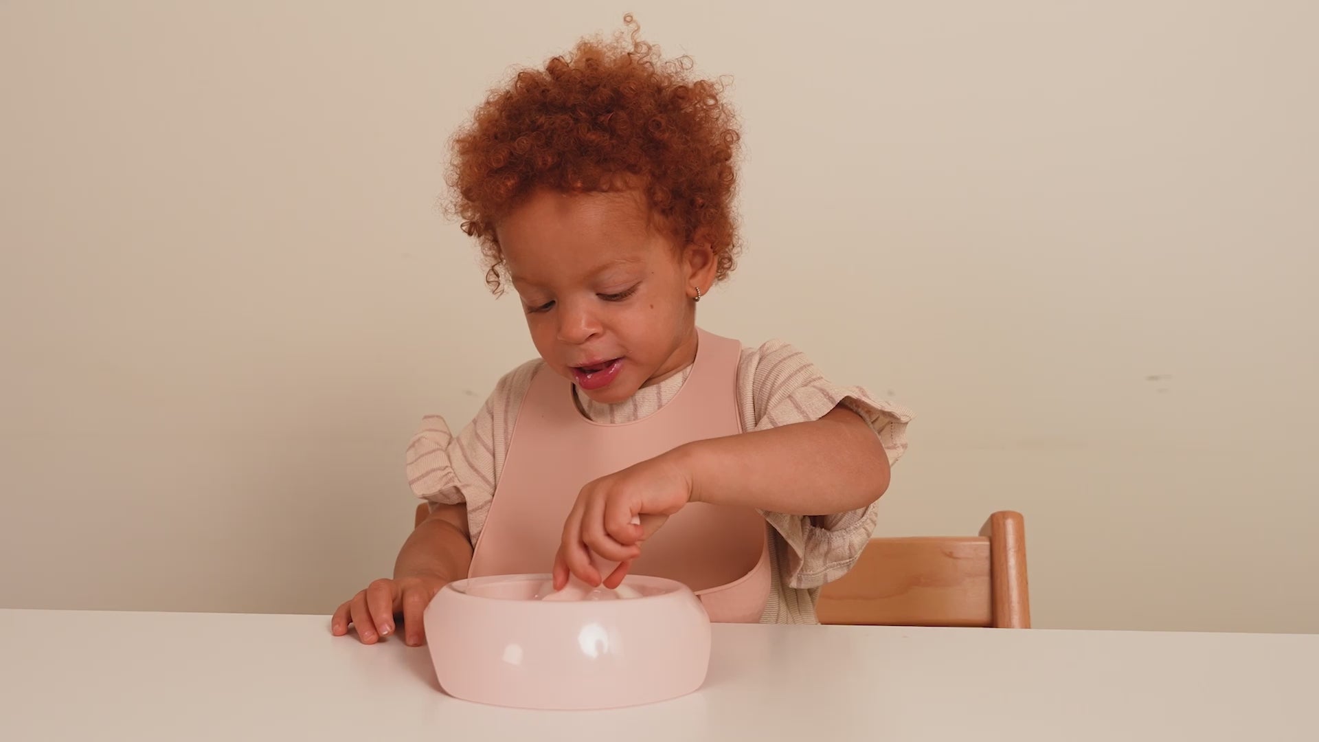 Enfants de 18 mois portant un bavoir en silicone Difrax, coloris nude et pistache, pendant le repas