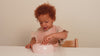 Enfants de 18 mois portant un bavoir en silicone Difrax, coloris nude et pistache, pendant le repas